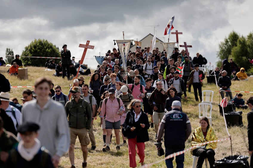 Pilgrims hold crosses, banners and flags as they arrive for the Mass, during the traditional Pentecostal pilgrimage from Paris to Chartres, in Sonchamp, near Paris, on June 8, 2025. From the church of Saint-Sulpice in Paris, thousands of people began their march towards Chartres on June 7, 2025 for the great traditionalist pilgrimage, which is attracting a record 19,000 Catholics this year, despite certain tensions with the episcopate. (Photo by STEPHANE DE SAKUTIN / AFP) (Photo by STEPHANE DE SAKUTIN/AFP via Getty Images)