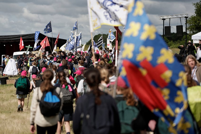 Pelgrins hold crosses, banners and flags as they arrive for the Mass, during the traditional Pentecostal pilgrimage from Paris to Chartres, in Sonchamp, near Paris, on June 8, 2025. From the church of Saint-Sulpice in Paris, thousands of people began their march towards Chartres on June 7, 2025 for the great traditionalist pilgrimage, which is attracting a record 19,000 Catholics this year, despite certain tensions with the episcopate. (Photo by STEPHANE DE SAKUTIN / AFP) (Photo by STEPHANE DE SAKUTIN/AFP via Getty Images)