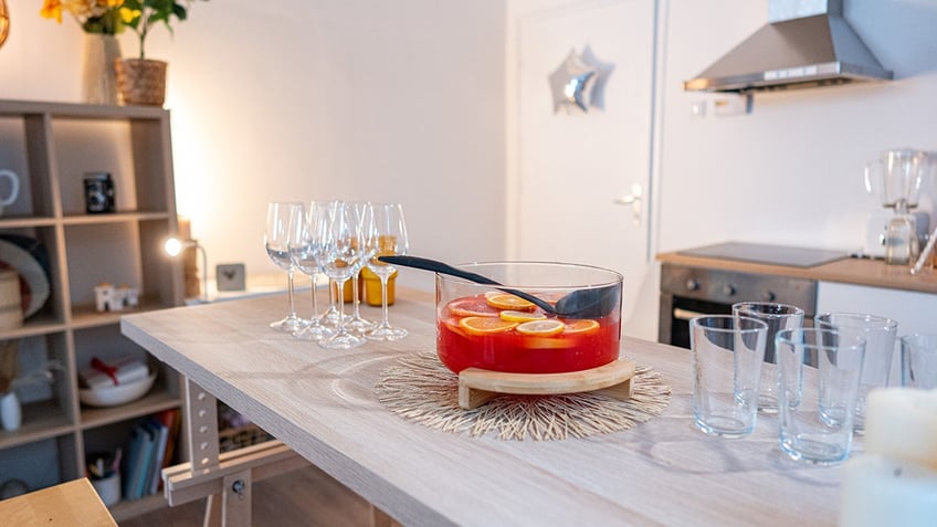 Drinking glasses and punch in a glass bowl, on the table in the kitchen