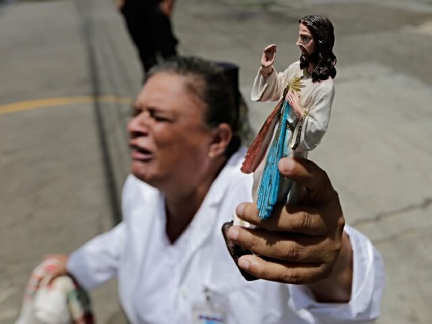 A woman kneels holding a religious figure as a caravan of the Catholic Church, including c