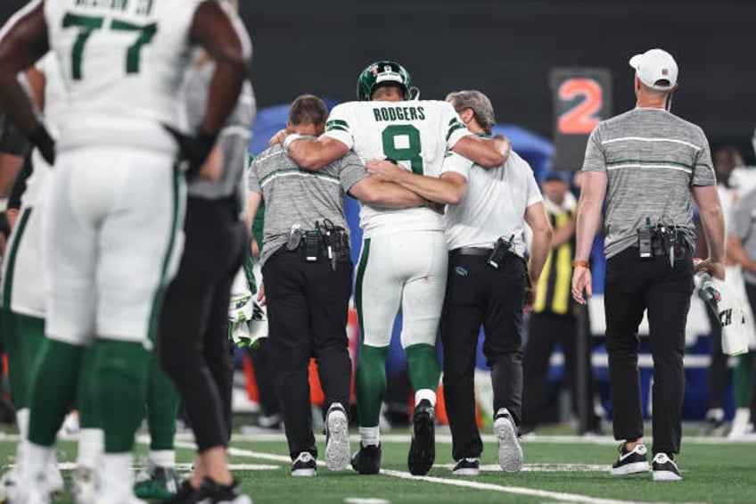 Aaron Rodgers of the New York Jets is helped off the field for an apparent injury during a game against the Buffalo Bills at MetLife Stadium on...