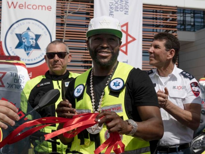 American boxing champion Floyd Mayweather, Jr., center, poses with red ribbons he cut afte