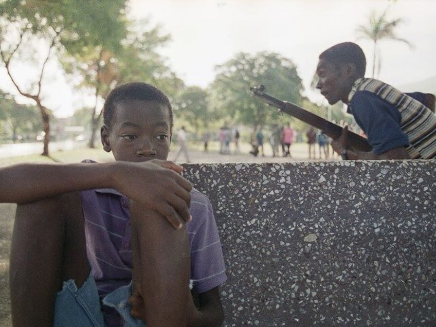 A boy sits in Port-au-Prince’s Champ de Mars Park as Haitian paramilitary recruits train