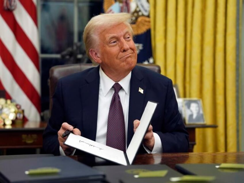 FILE - President Donald Trump signs executive orders in the Oval Office of the White House