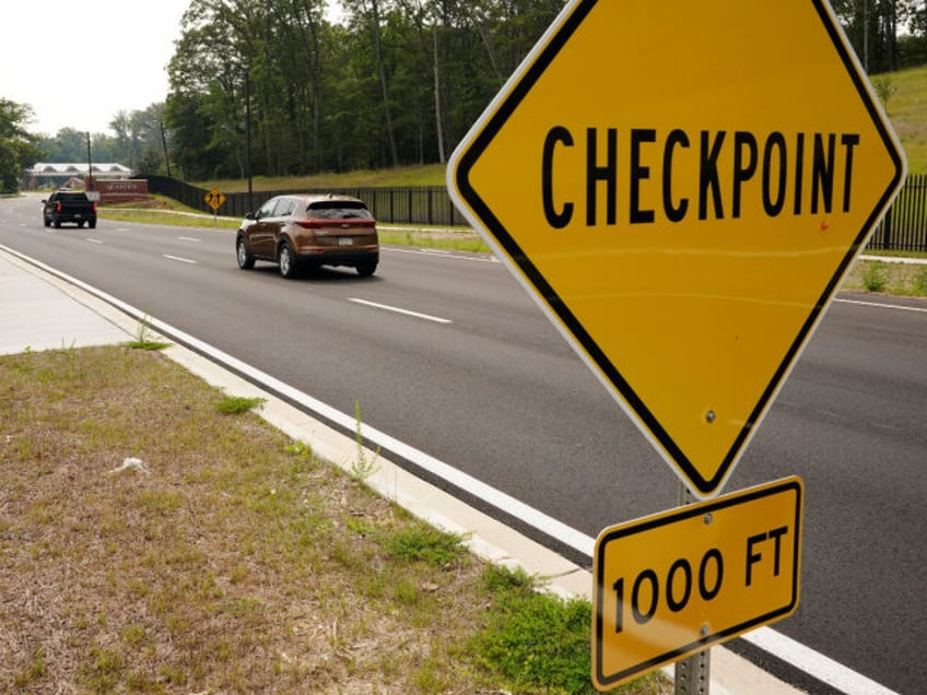 Traffic drives past a sign warning of a checkpoint at the entrance of Marine Corps Base Qu