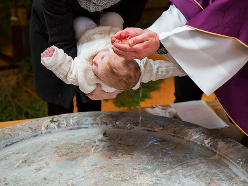 Priest is baptizing little baby girl in a church