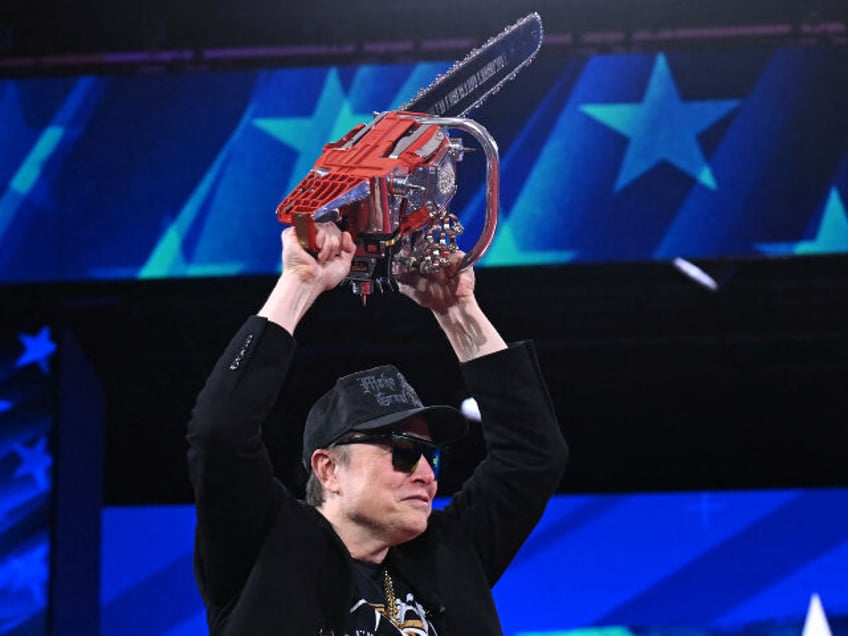 Elon Musk holds a chainsaw reading "Long live freedom, damn it" during the annua