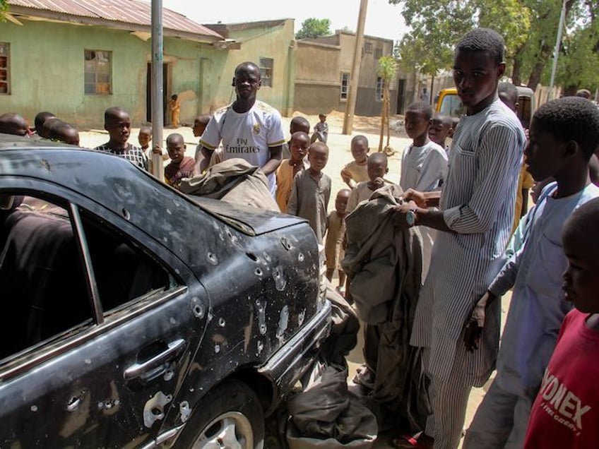 The wreckage of a car hit by an attack led by Boko Haram members is seen surrounded by residents of the Adam Kolo district of Maiduguri on February 24, 2021. - Boko Haram jihadists attacked the Nigerian city of Maiduguri in the volatile northeast, killing 10 to 17 people, including nine children who were playing football in a field, local militia told AFP February 24, 2021. (Stringer/AFP via Getty Images)