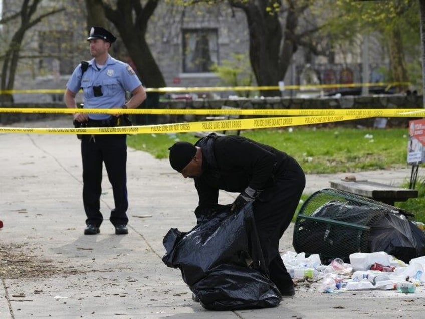 A person picks up debris in the aftermath of a shooting at an Eid event in Philadelphia, W