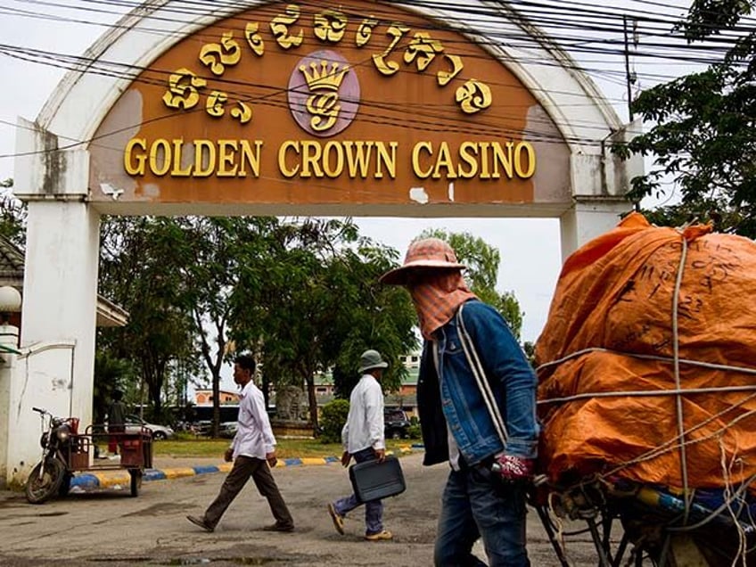 Pedestrians pass by the Golden Crown Casino in the border town of Poi Pet, Cambodia, on Thursday, Jan. 12, 2012. Thailand and Cambodia both claim 26,000 square kilometers of waters in the Gulf of Thailand that may contain oil and gas. Photographer: Brent Lewin/Bloomberg via Getty Images