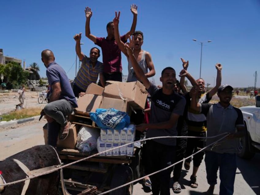 Palestinians wave to the camera as they carry boxes and bags containing food and humanitar