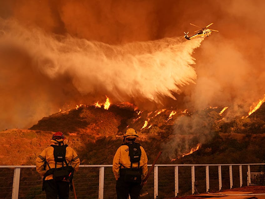 Firefighters watch as water is dropped on the Palisades Fire in Mandeville Canyon on Satur