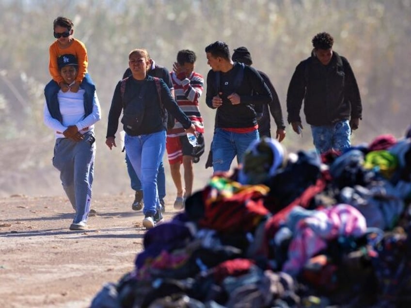 EAGLE PASS, TEXAS - JANUARY 08: Immigrants from Venezuela walk past a pile of discarded migrant clothing after crossing the Rio Grande into the United States on January 08, 2024 in Eagle Pass, Texas. Immigrant crossings in the area have dipped dramatically since a major surge in the last months …