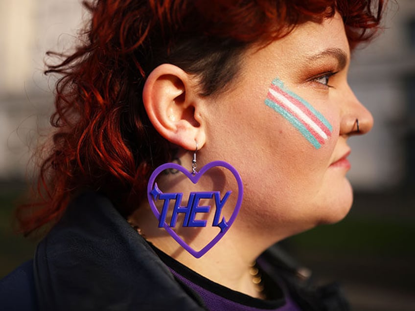 Trans rights activist Lilly wears an earring featuring a 'they' pronoun symbol, during a p