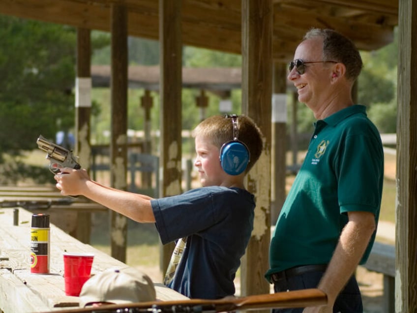 Man Supervises Teenage Boy Shooting Hand Gun At Target At Shooting Range In Ocala National