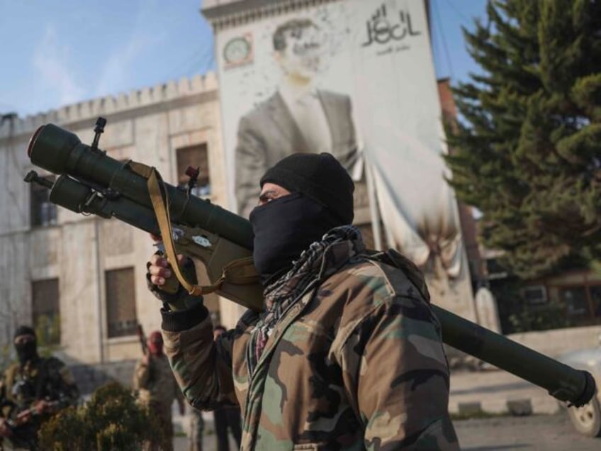 A Syrian opposition fighter holds a rocket launcher in front of the provincial government