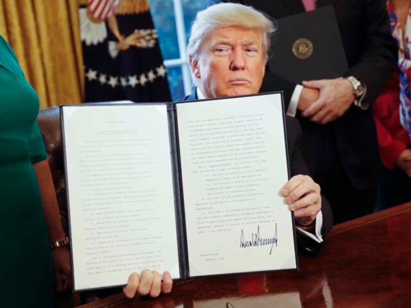 President Donald Trump holds up an executive order after his signing the order in the Oval