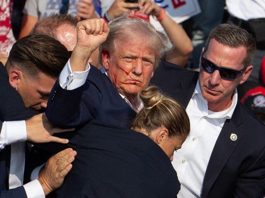 US Republican candidate Donald Trump is seen with blood on his face surrounded by secret s