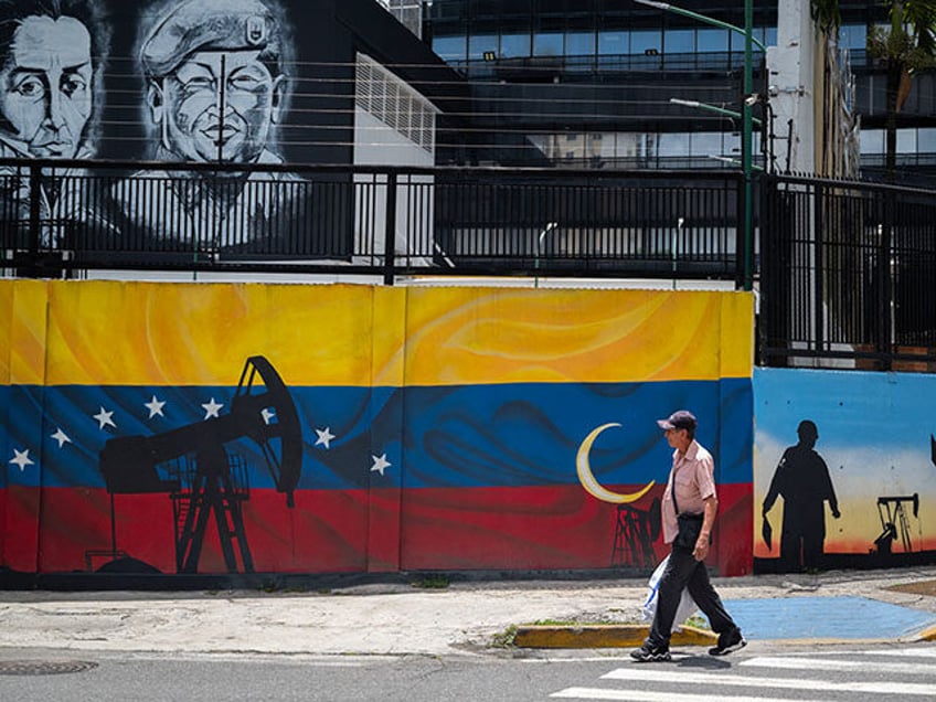 A man walks past a mural painted on the wall outside the headquarters of PDVSA (Petroleros de Venezuela, SA) in Caracas, on September 13, 2023. (Photo by Miguel Zambrano / AFP) (Photo by MIGUEL ZAMBRANO/AFP via Getty Images)