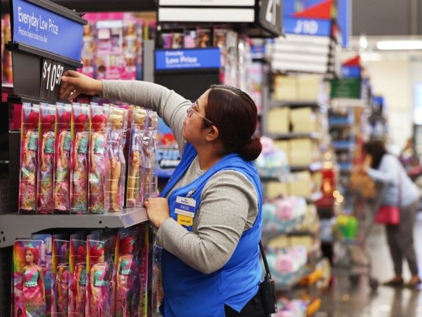 An employee adjusts a price label for Barbie dolls displayed for sale ahead of Black Frida