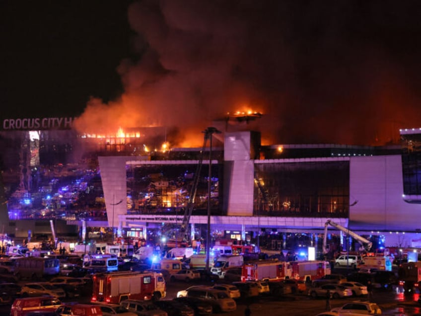 Emergency services vehicles are seen outside the burning Crocus City Hall concert hall fol