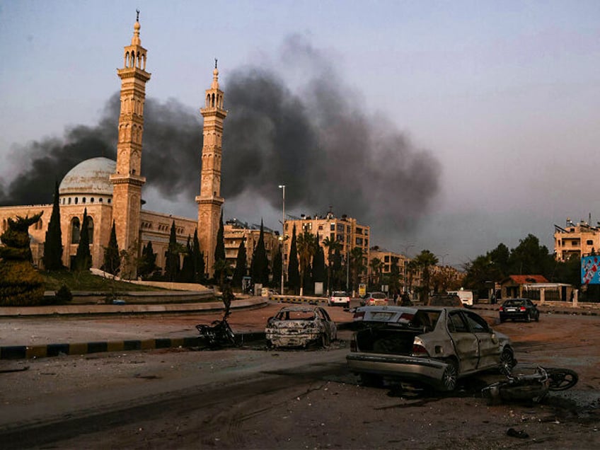 TOPSHOT - CORRECTION / Smoke billows in the distance as damaged cars are seen at the site