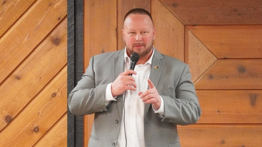 Randy Niemeyer in gray coat holding microphone