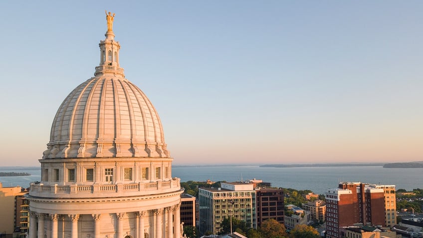 Wisconsin capitol dome close up on lower left thirds, blue sky sunset and a city in the background