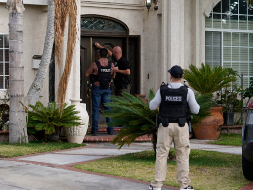 U.S. Immigration and Customs Enforcement agents knock at a residence after an arrest of an