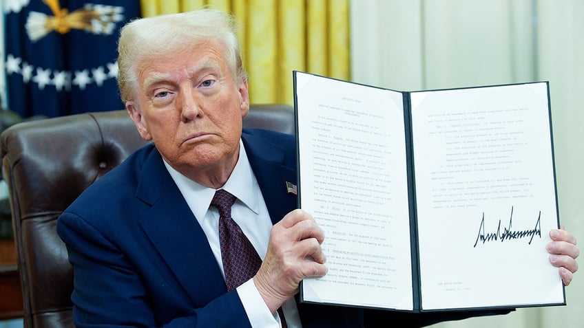 President Donald Trump holding up signed document