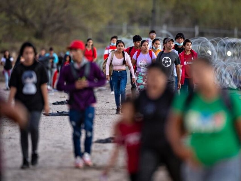 EAGLE PASS, TEXAS - DECEMBER 17: Migrants walk towards a field processing center after cro