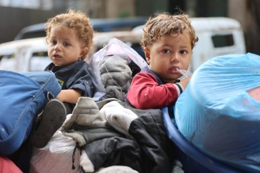 Palestinian children sit with family belongings in the back of a makeshift trolley as they