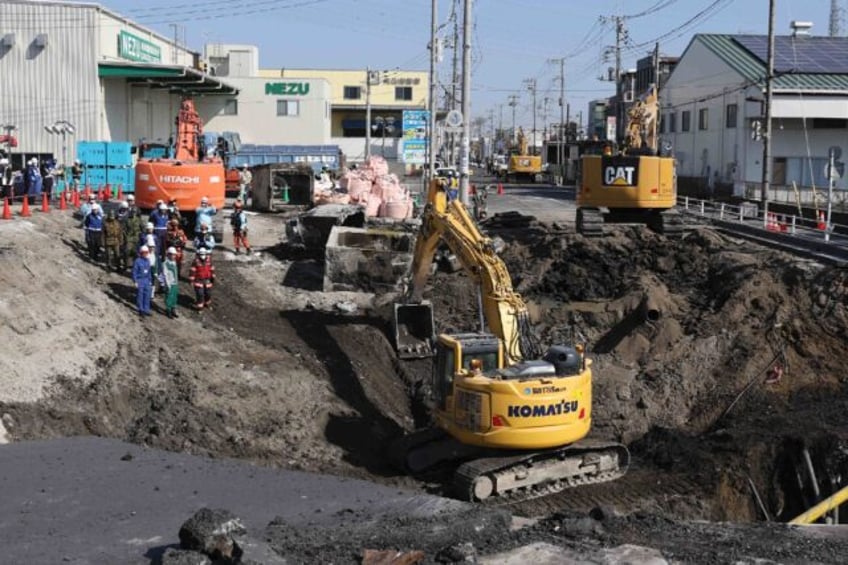 Excavators and rescue personnel working to construct a slope at the sinkhole site