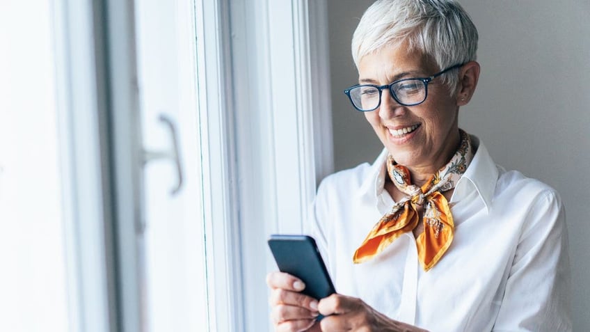 Older woman looking at her phone while she texts.