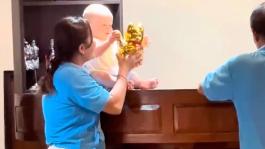 A restaurant employee entertains a baby whose parents are vacationing in Bali, Indonesia.