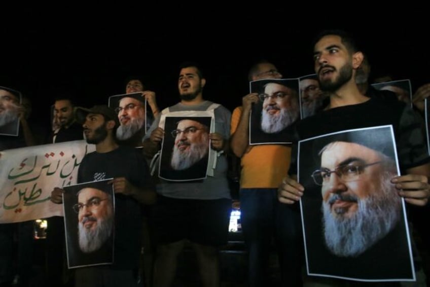 Demonstrators hold pictures of slain Hezbollah leader Hassan Nasrallah during a protest vi