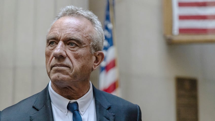 RFK Jr standing in front of an American flag