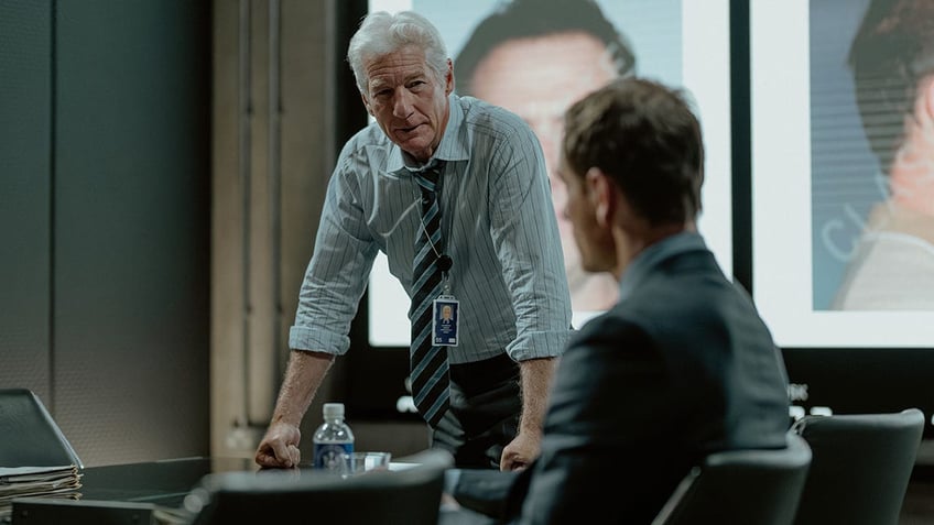 Richard Gere leaning on a table in a scene from "The Agency."