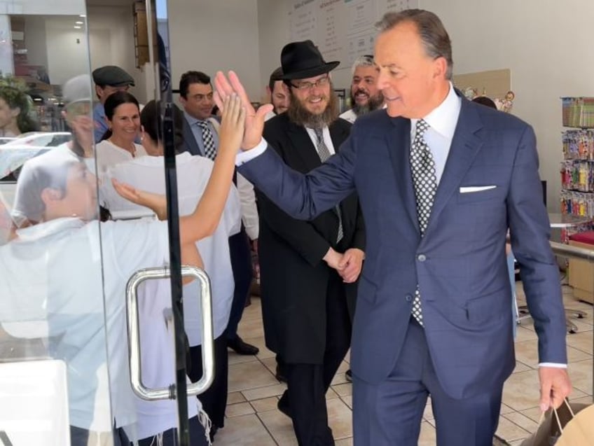 Rick Caruso high-fives a young supporter at Munchie's kosher candy store during a vis