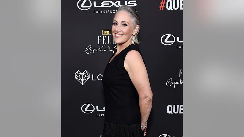 Ricki Lake in a black dress turns to the side and smiles for a photo