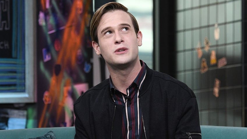 Tyler Henry in a black polo shirt looks up and to his left in a photograph