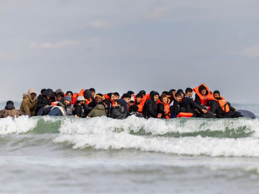 Migrants board a smuggler's boat in an attempt to cross the English Channel, on the beach