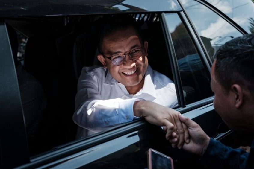 Presidential candidate Anies Baswedan shakes hands with a supporter as he arrives for a campaign rally