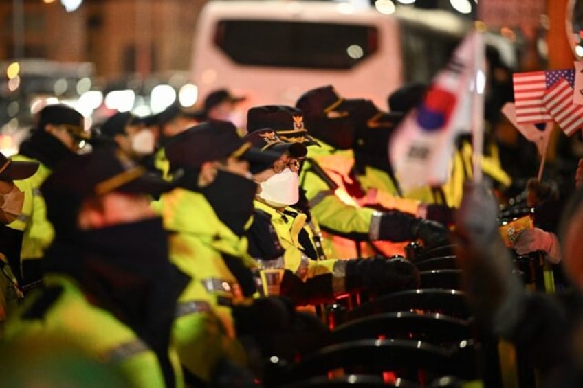 Police officers set up barricades in front of people taking part in a rally to support Sou