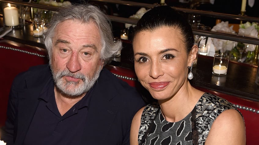 Robert De Niro in a black shirt sits next to his daughter Drena De Niro