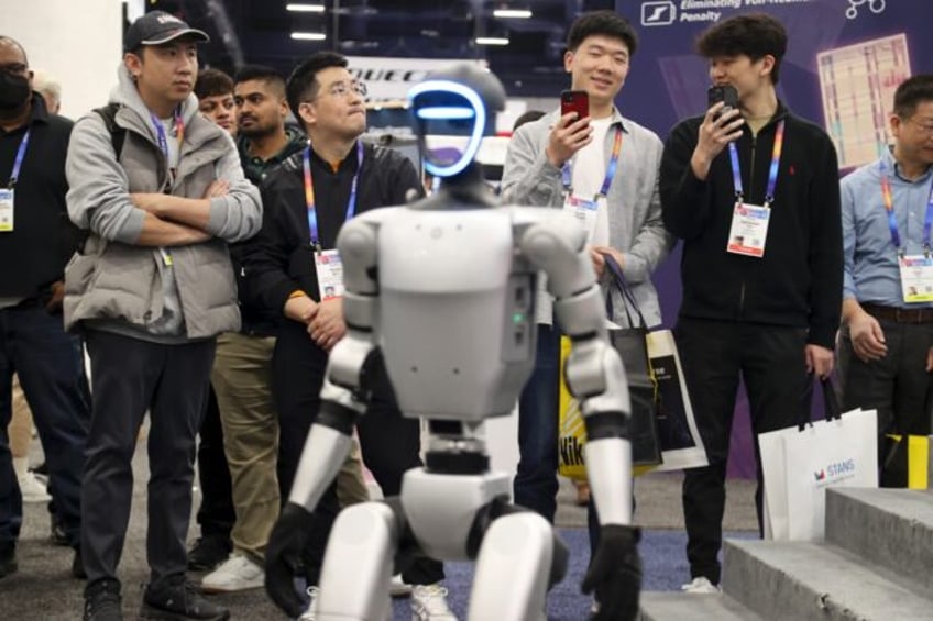 Attendees watch as a robot walks around during a demonstration at the Unitree Robotics boo