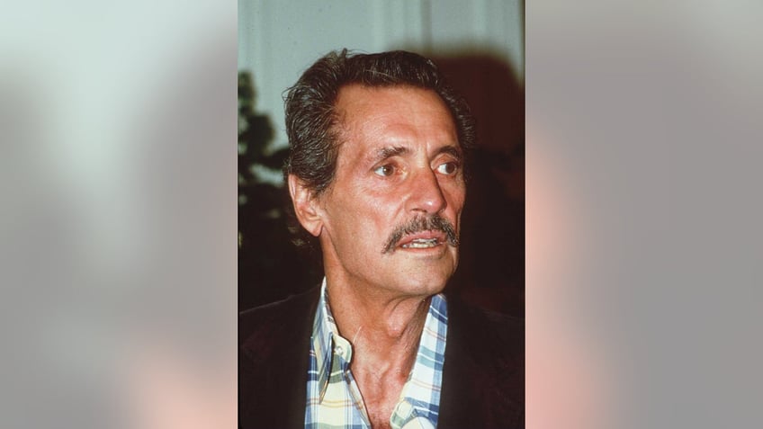 A close-up of Rock Hudson wearing a plaid shirt and a dark blazer