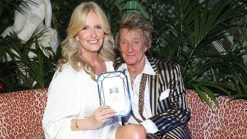 Rod Stewart in a pinstriped satin jacket with wife Penny in white