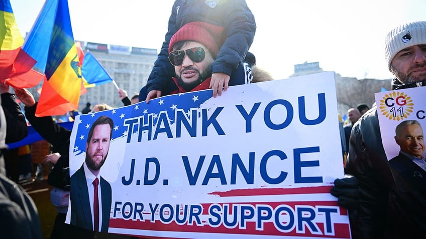 Georgescu supporter holds sign thanking JD Vance