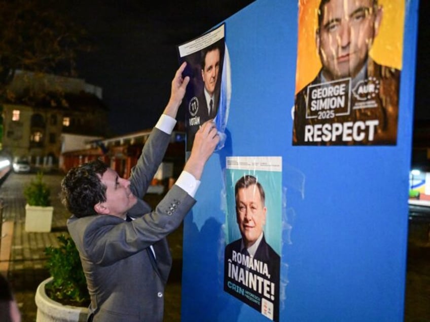 Mayor of Bucharest and presidential candidate Nicusor Dan pastes a campaign poster of hims